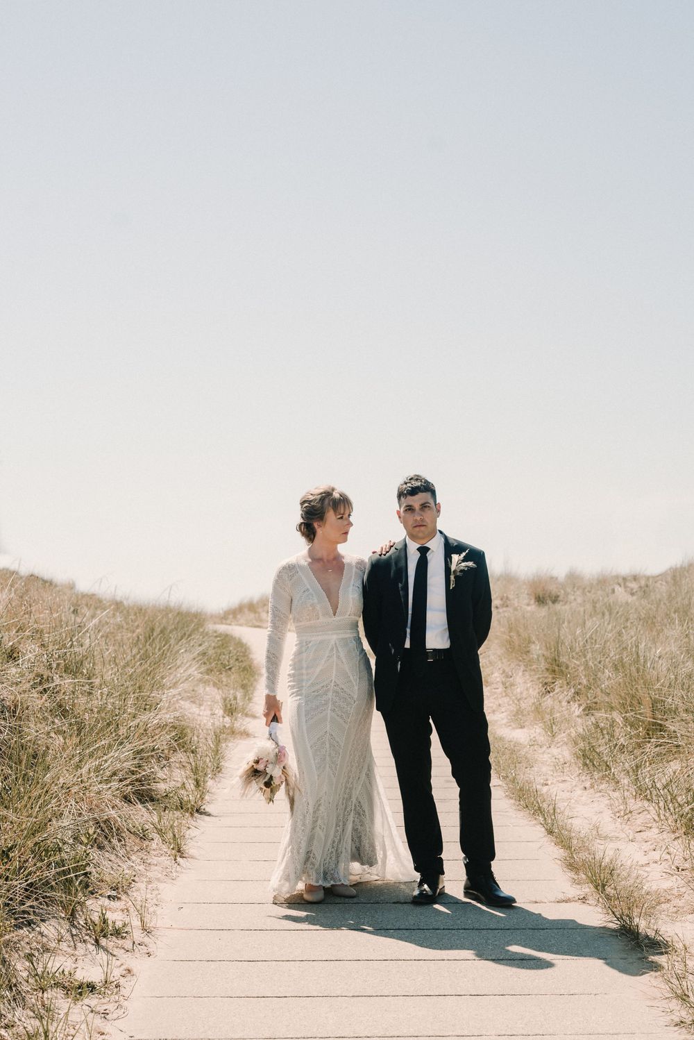 Newlyweds standing together on sandy dunes