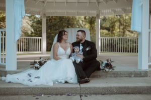Newlyweds seated with their dog beneath a gazebo